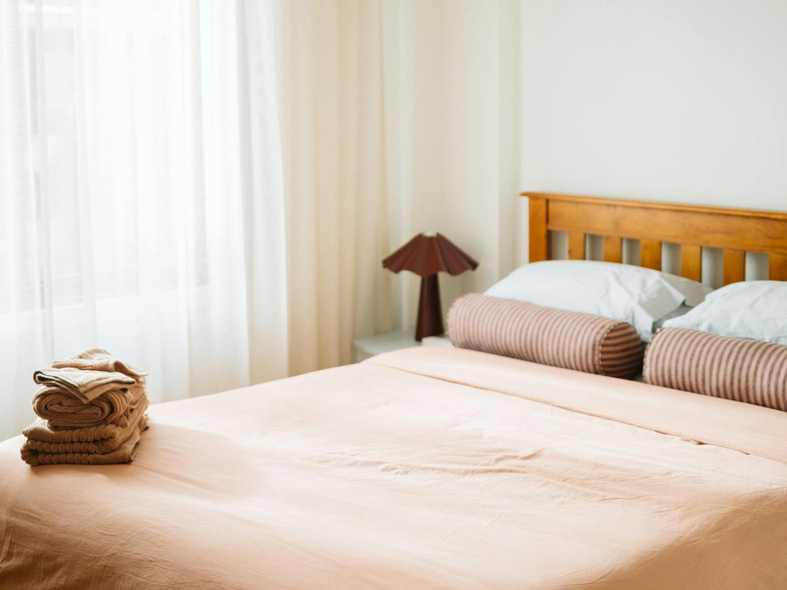 Light-filled queen bedroom with luxury linen and floor-to-ceiling sheer curtains, creating an airy,