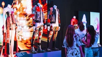 Korean fashion being displayed on mannequins in an exhibition and three young girls looking at them