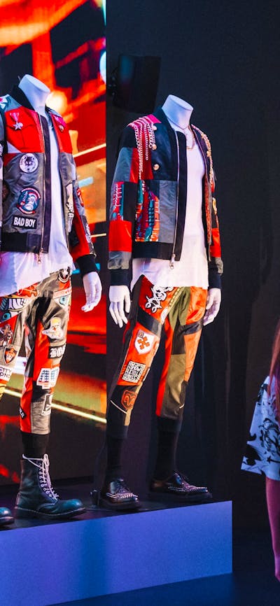 Korean fashion being displayed on mannequins in an exhibition and three young girls looking at them