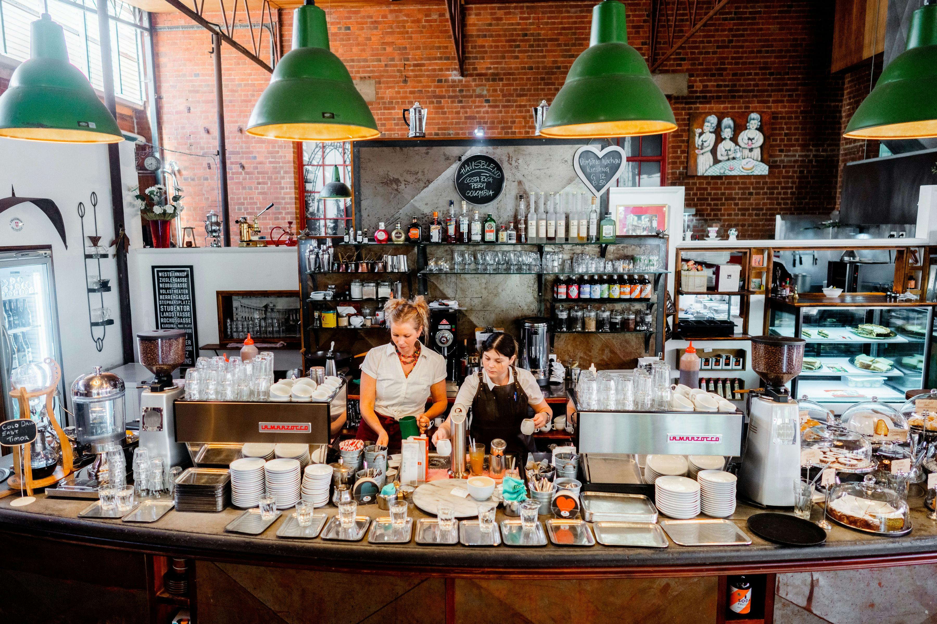 coffee house counter showing two staff and coffees cakes