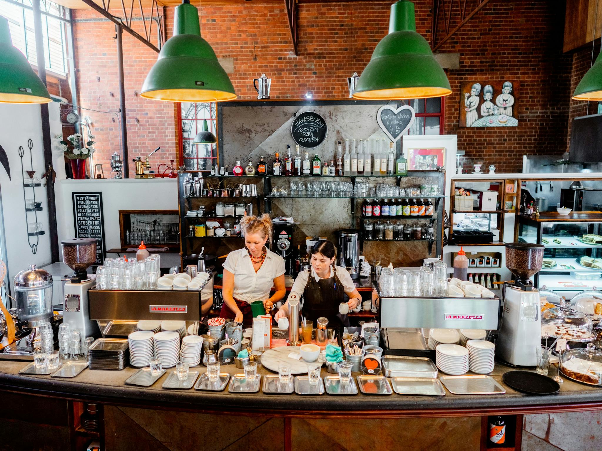 coffee house counter showing two staff and coffees cakes