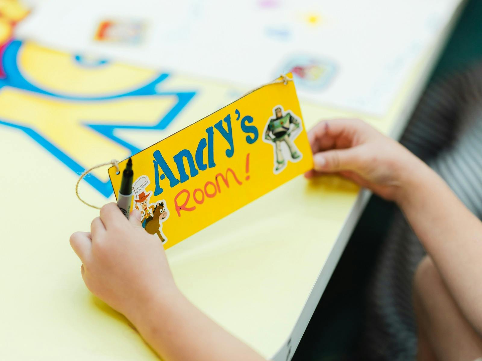 Hands holding up a kids craft Andy's Room sign
