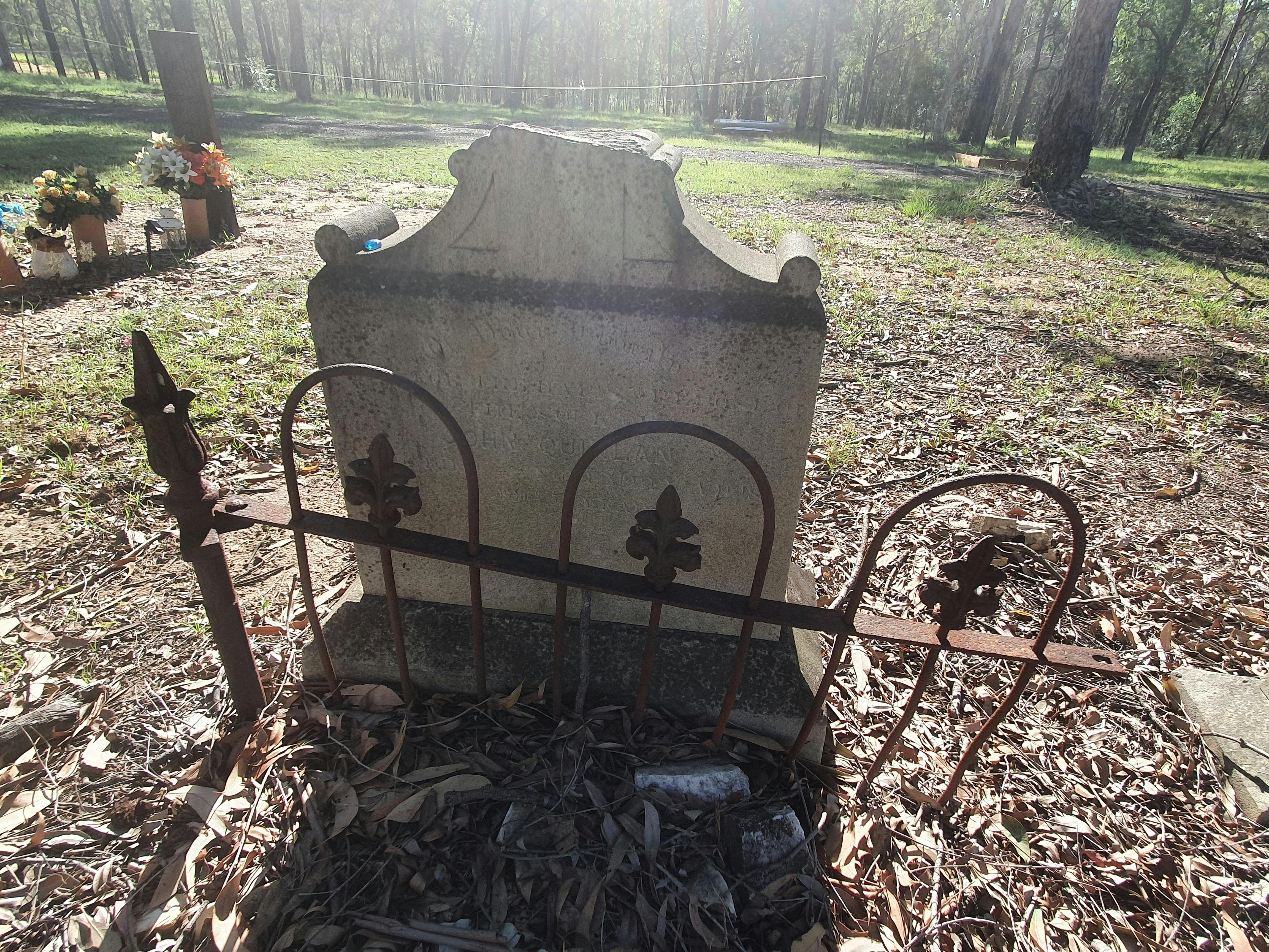 Grave stone behind fencing with light shining on it