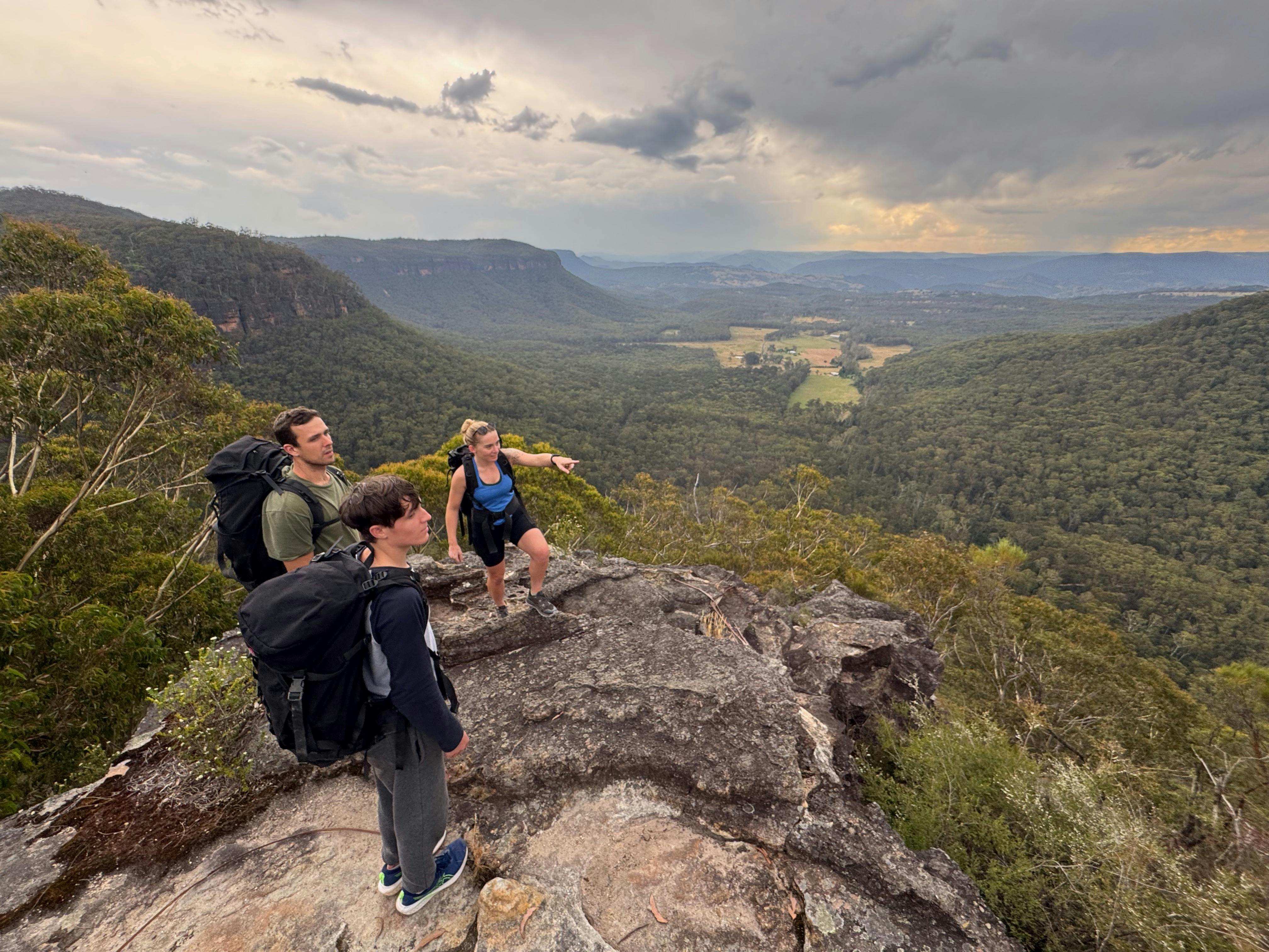 등반가들은 뒤로 메갈롱 계곡의 멋진 전망을 바라보며 바위 노두 위에 서 있습니다.