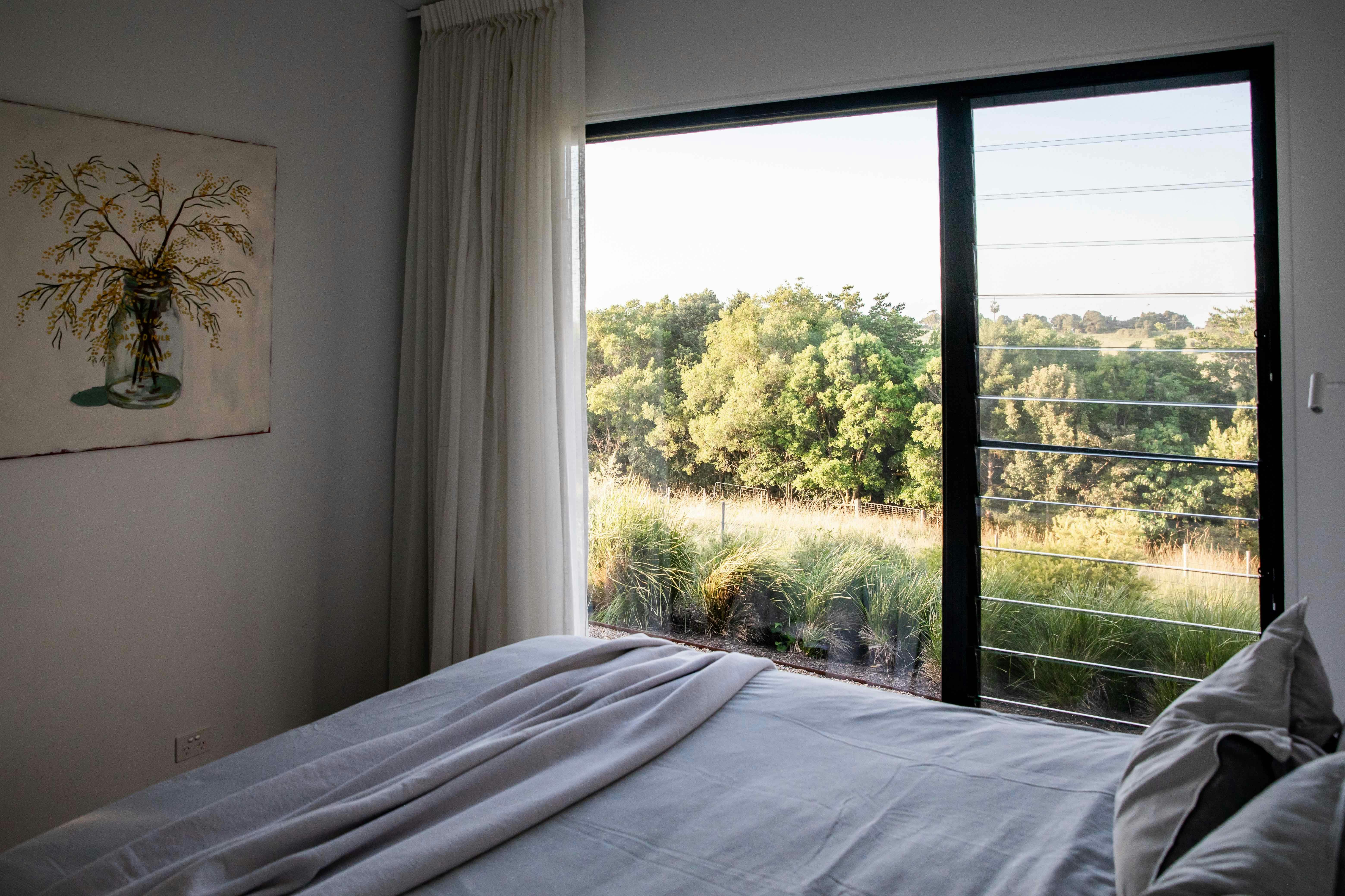 Main bedroom with cozy linens and rolling hills view