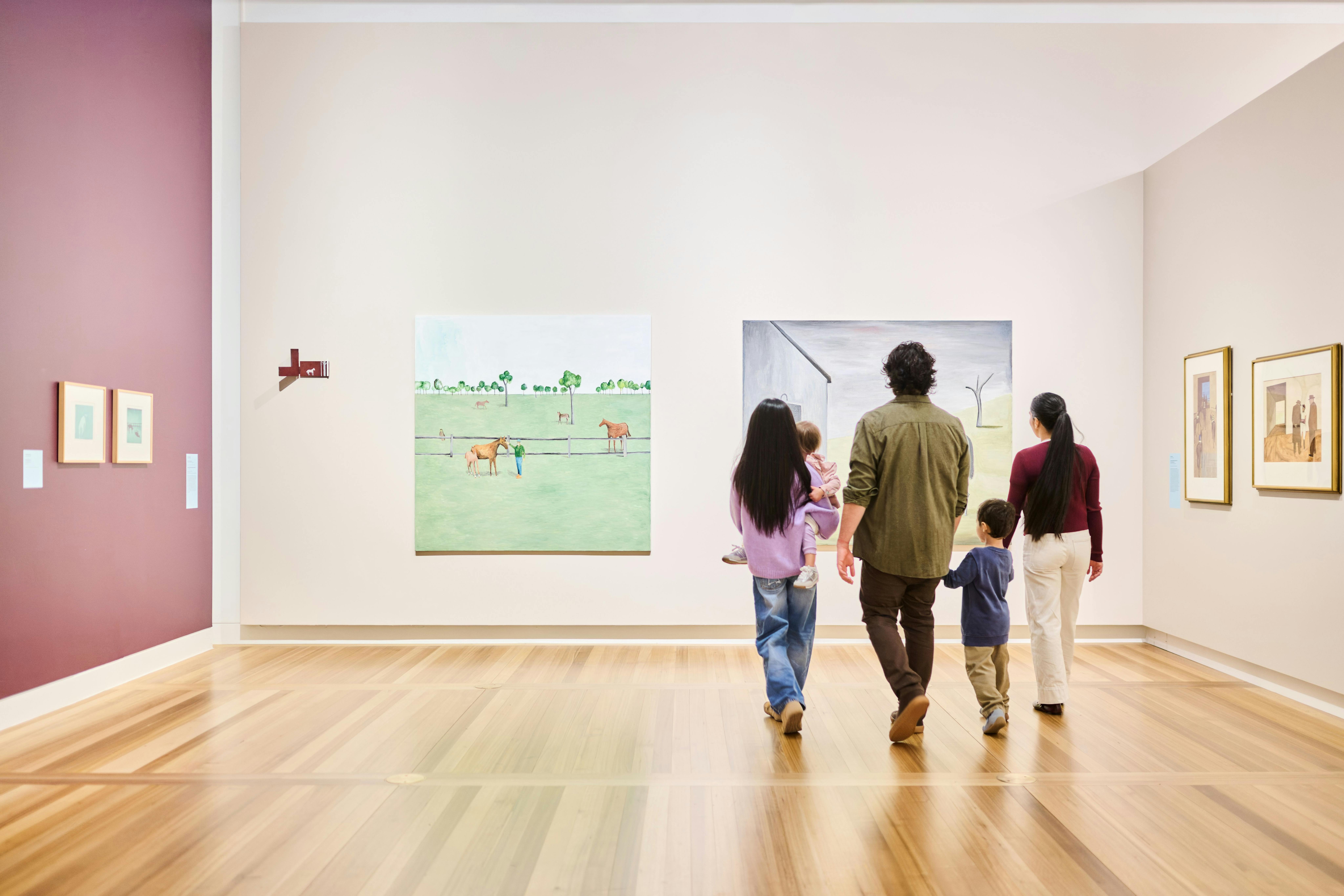 A family of five walking in a large, brightly lit gallery featuring many portraits.