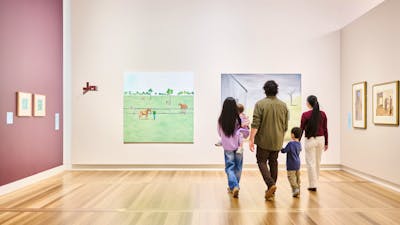 A family of five walking in a large, brightly lit gallery featuring many portraits.