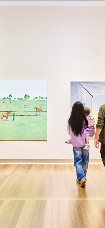 A family of five walking in a large, brightly lit gallery featuring many portraits.