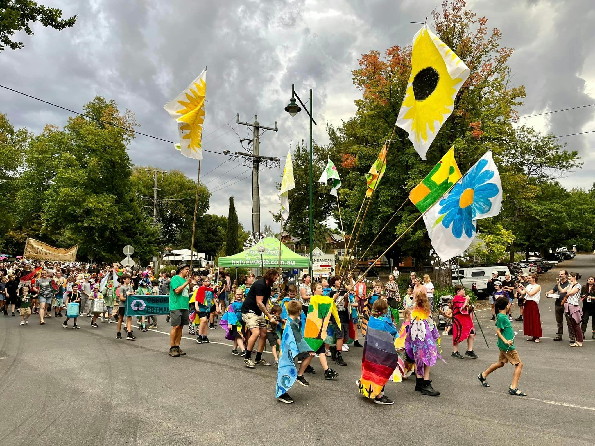 Children's street parade wearing hand made costumes and flying large painted flower flags