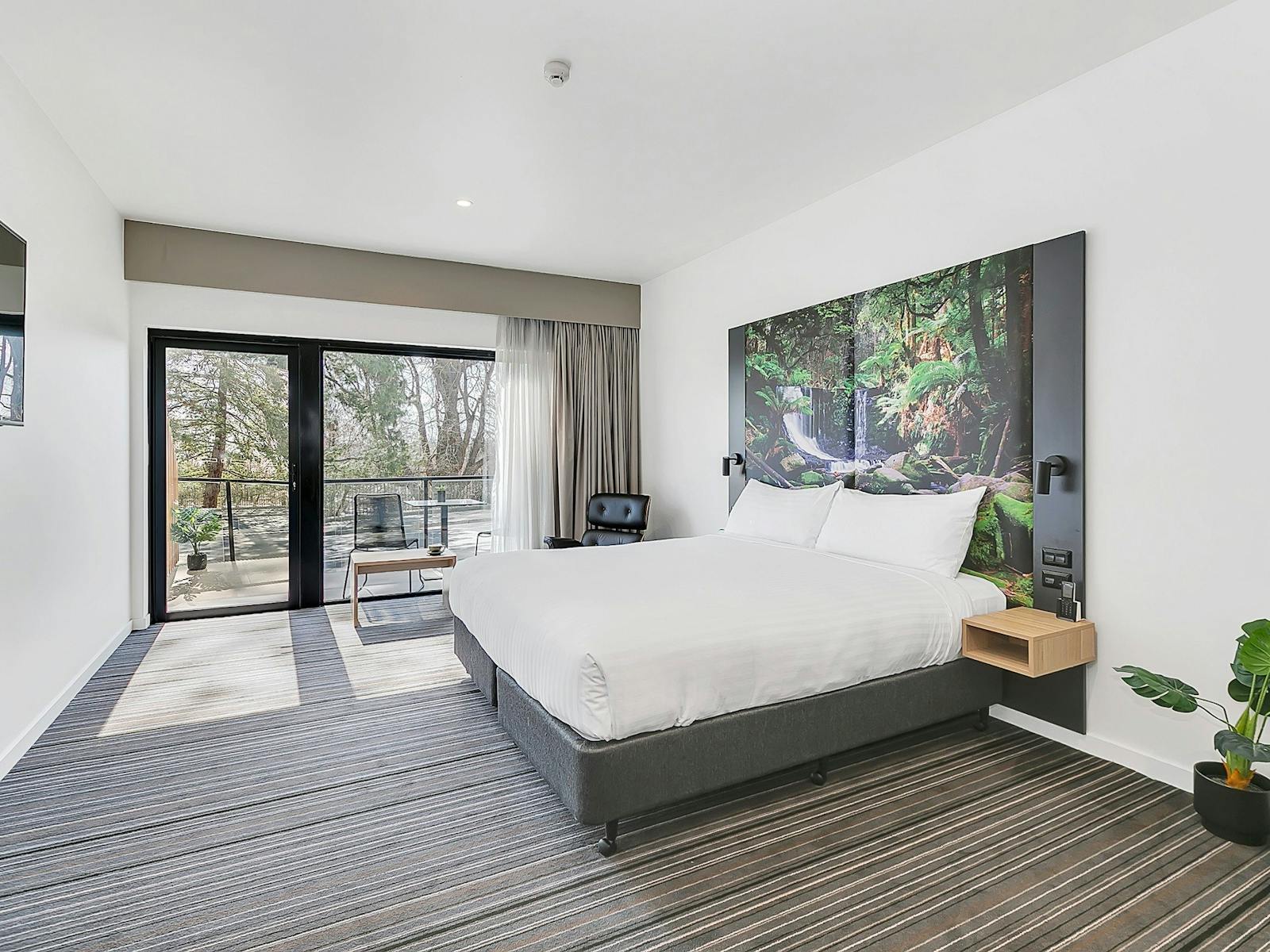 Guest accommodation room, with king bed and ample space, large window/glass door to small balcony.