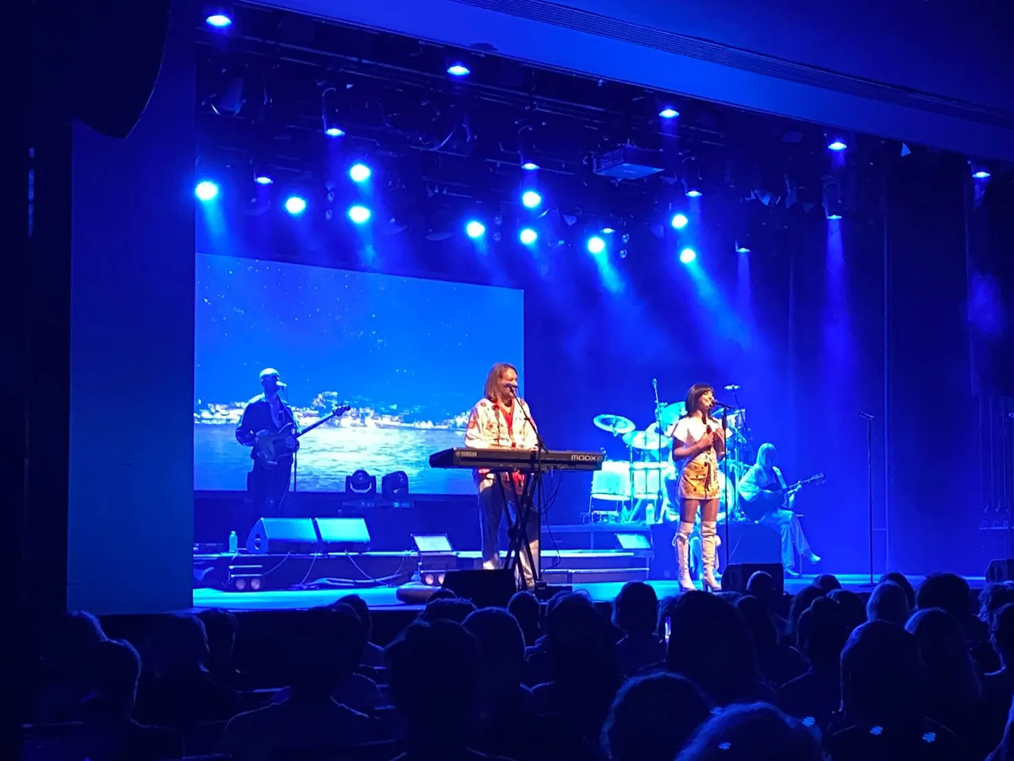 Blue lighting on stage with a singer and man on piano