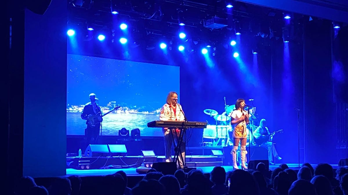 Blue lighting on stage with a singer and man on piano