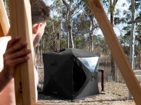 Person looking on at a black tent structure, Soulfire wood fired sauna, thinking about firing it up.