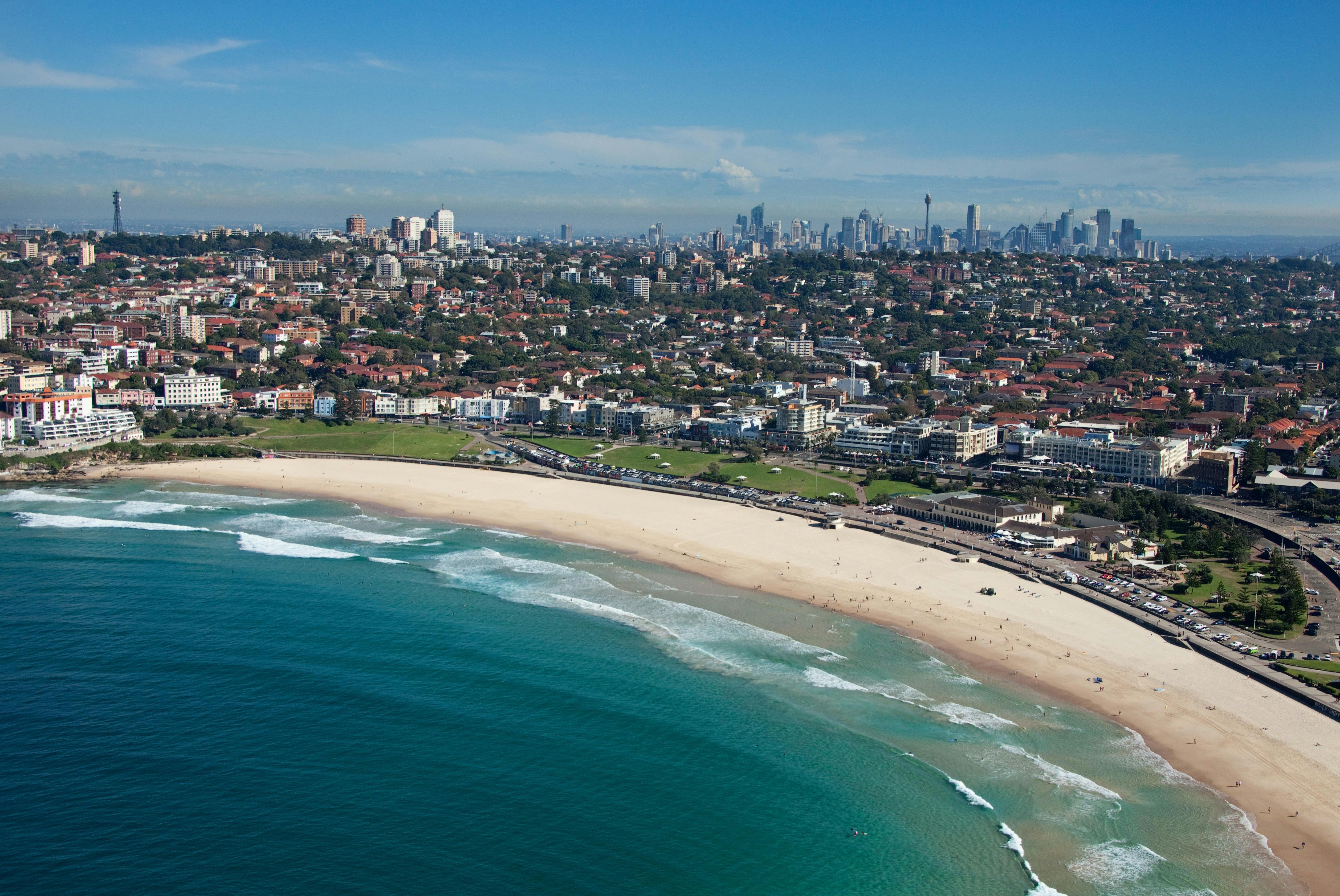Aerial of Bondi Beach in the morning with Sydney CBD in the background.