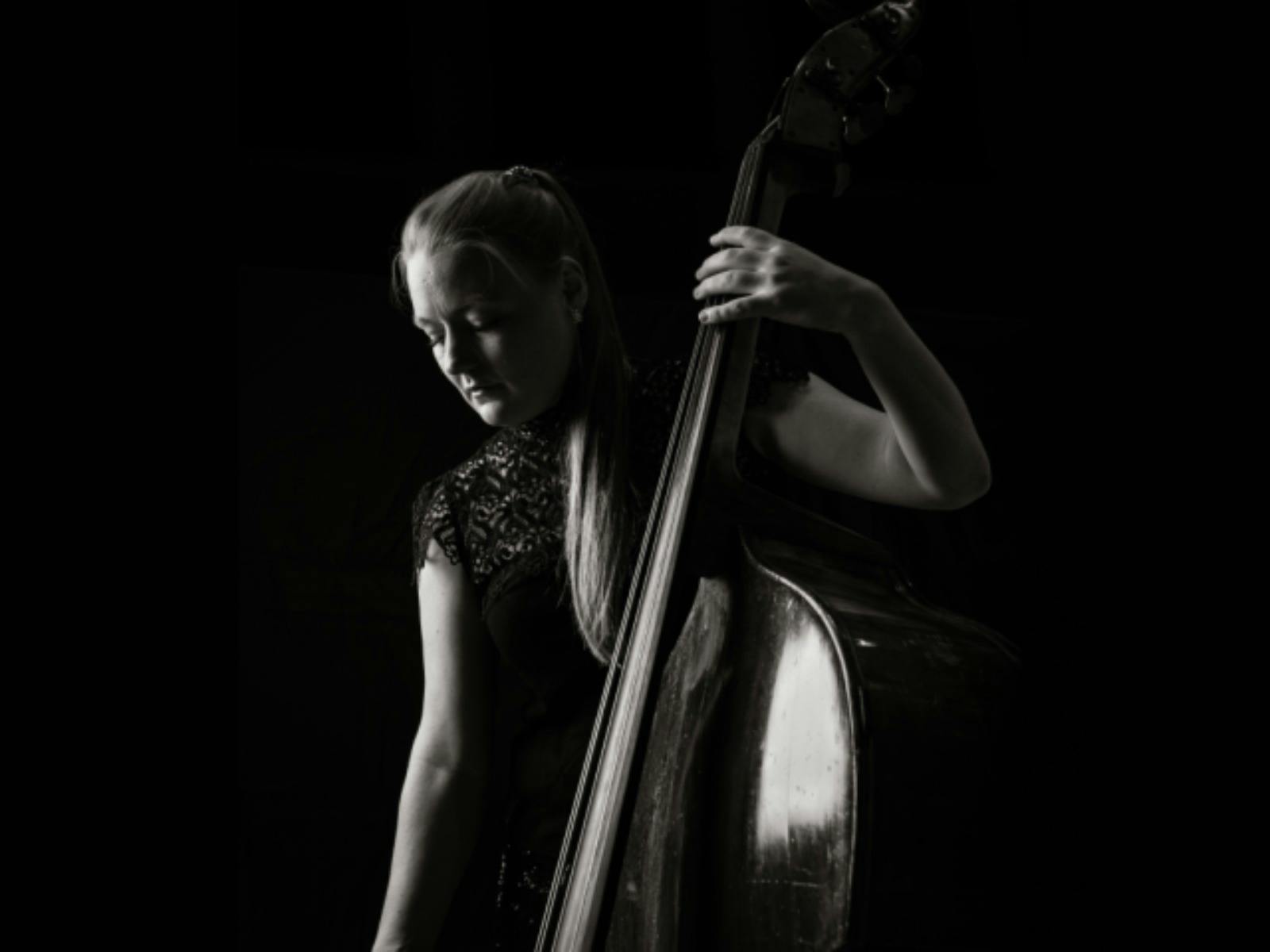 Black-and-white portrait of a double bassist in profile, looking toward the light