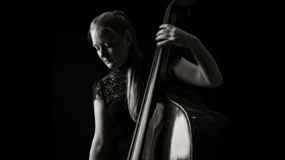 Black-and-white portrait of a double bassist in profile, looking toward the light