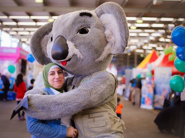 Koala character hugging woman