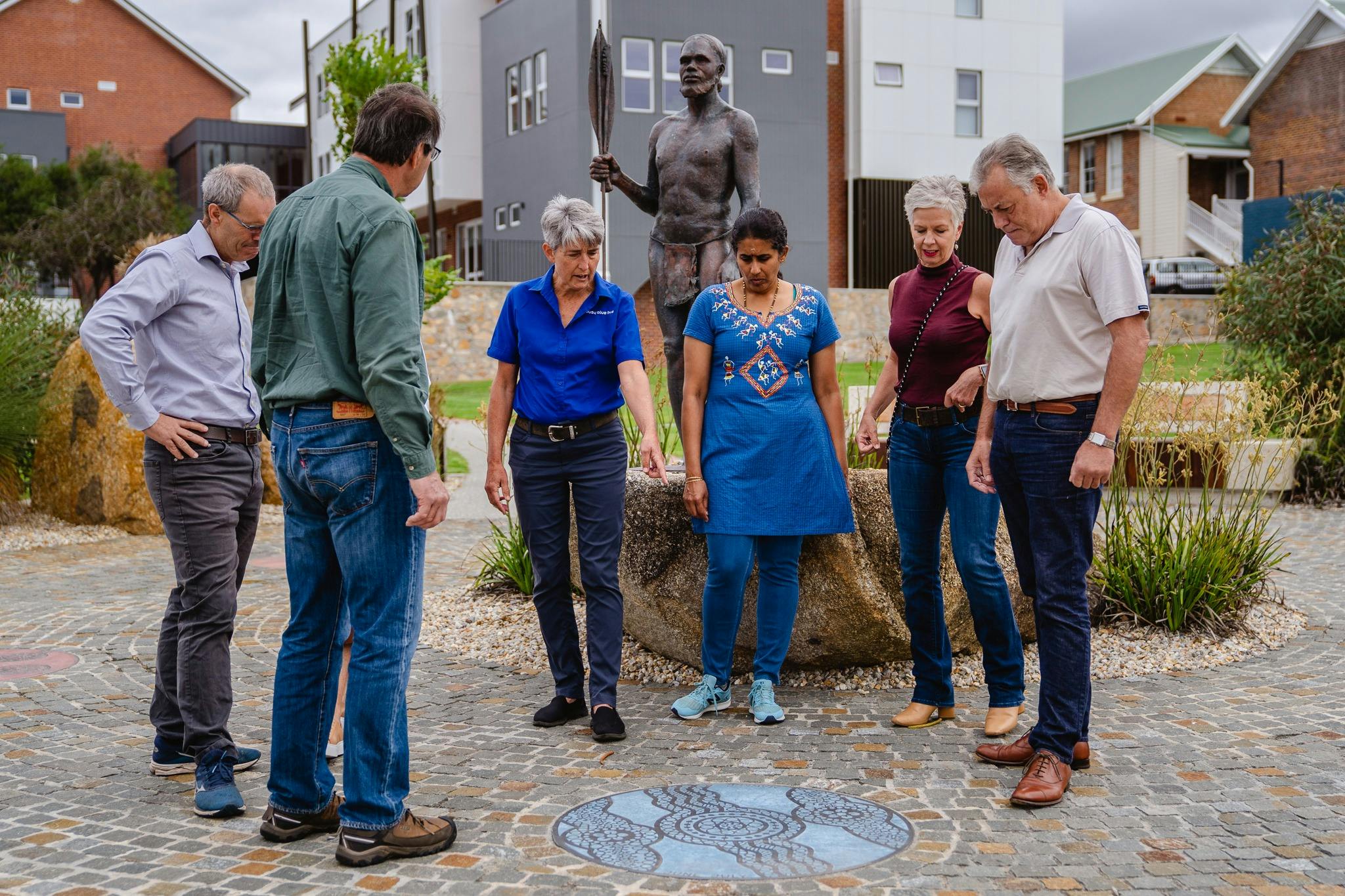 group of people looking at groudn where tour guide is pointing