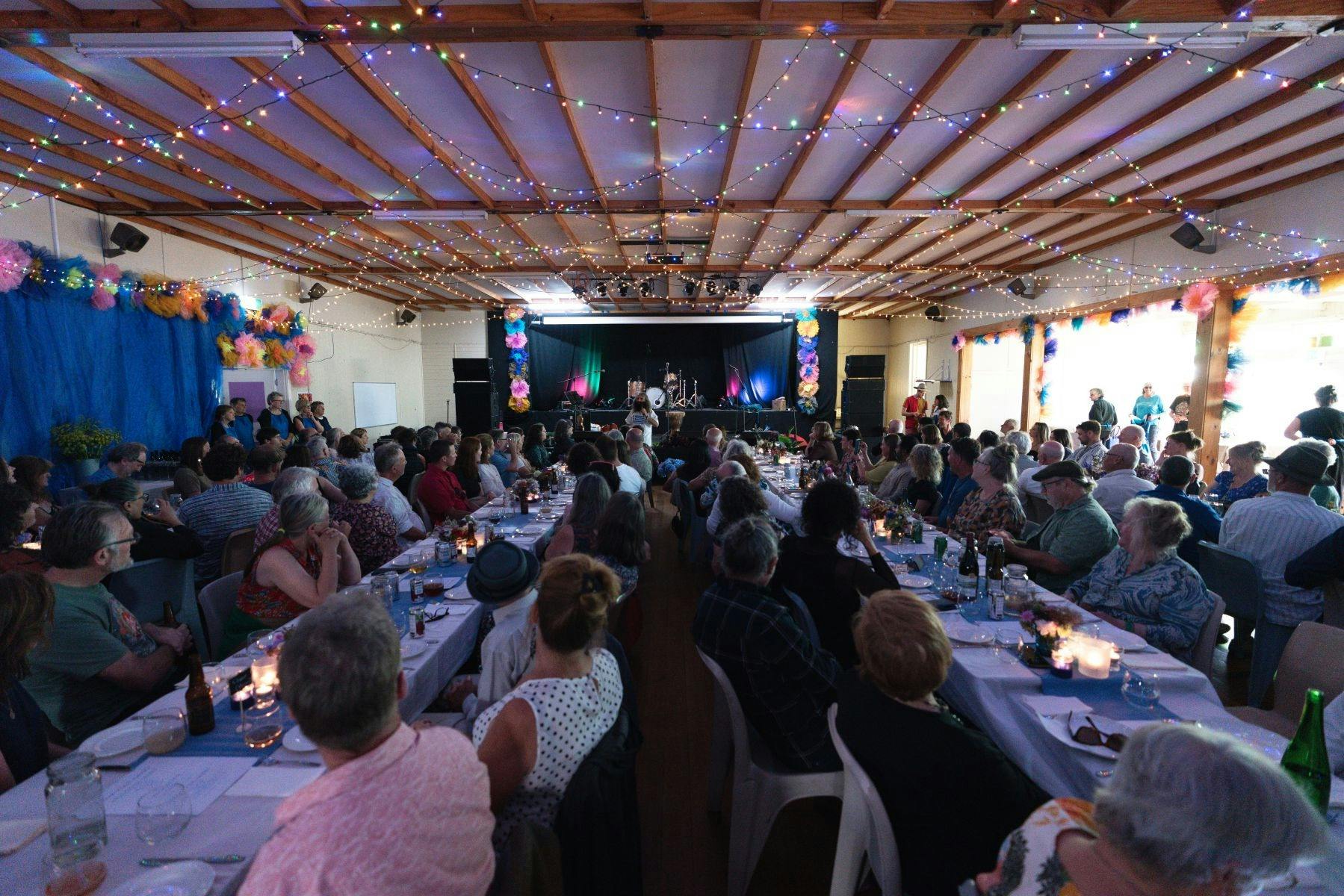 Two long tables side by side with people eating and drinking
