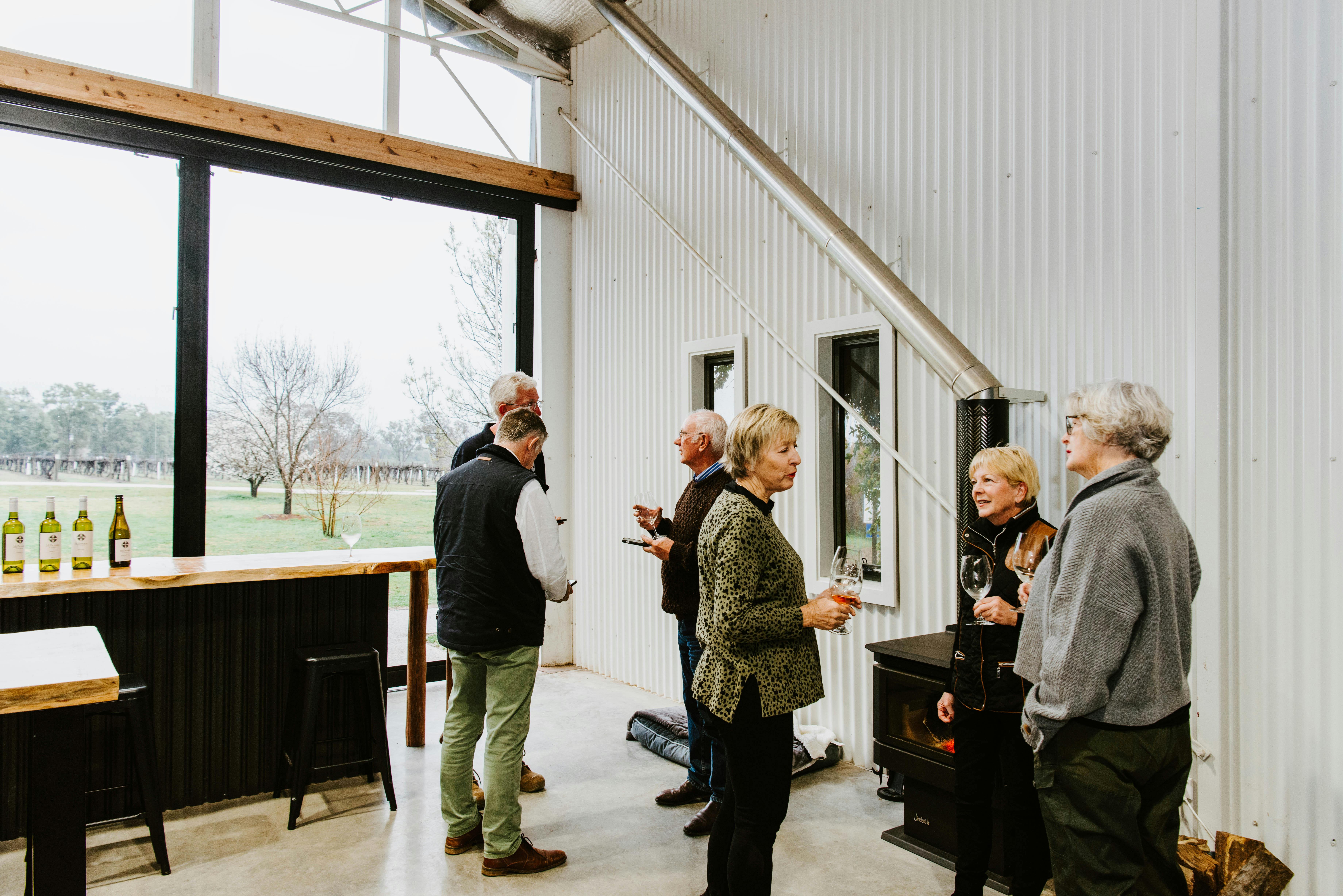 Picture of a group of friends around the wood burner enjoying a wine tasting at McIntosh Estate.