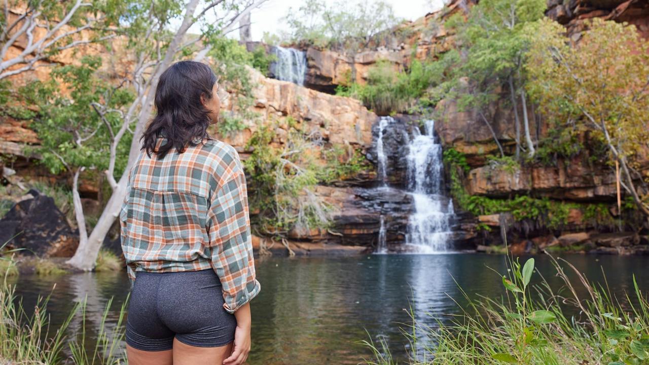 Woman standing looking at the Galvans Gorge Waterfall on the Gibb River Road.