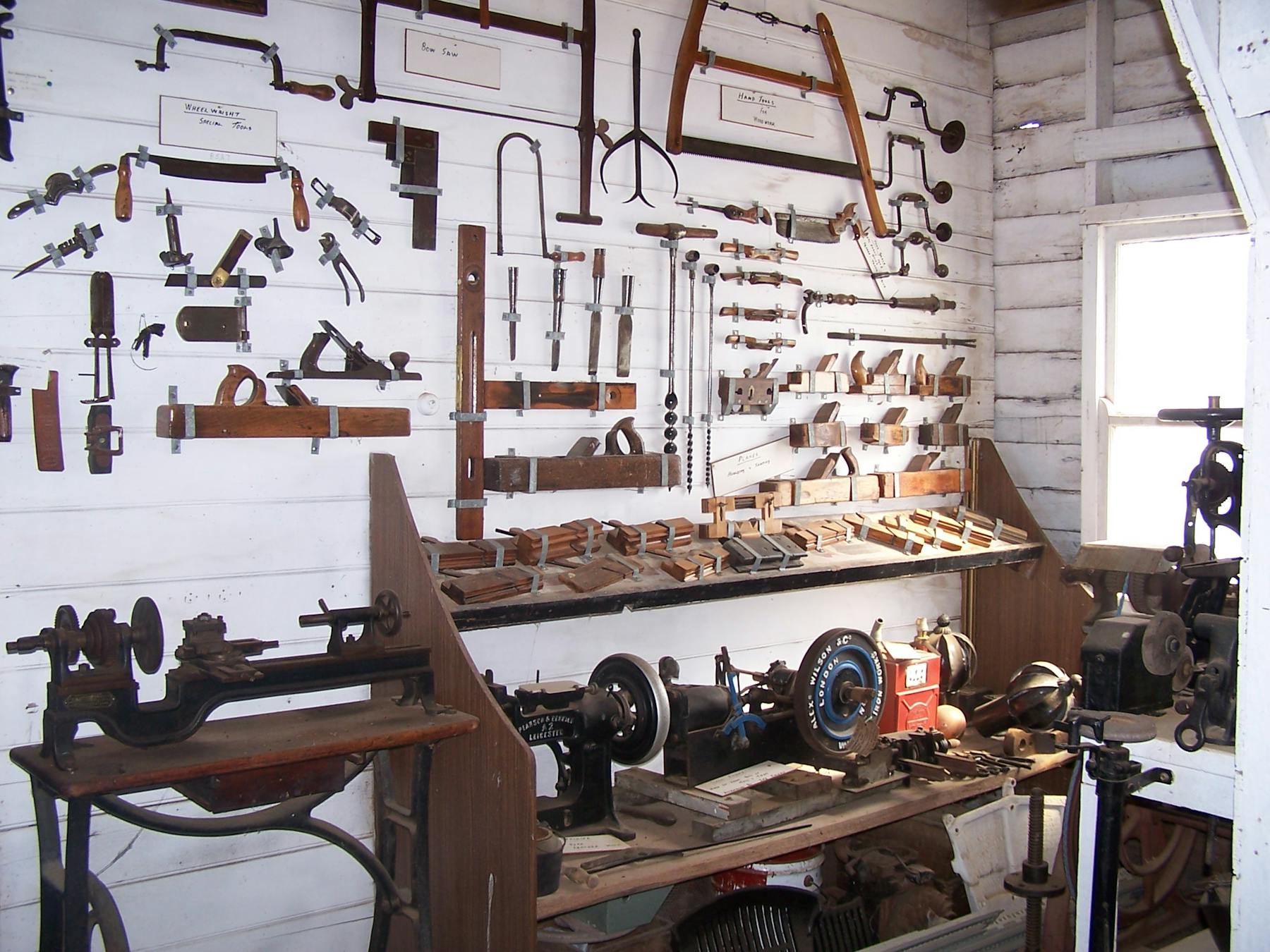 A collection of old wheel wright and wood working tools, industrial sewing machine and steam engine