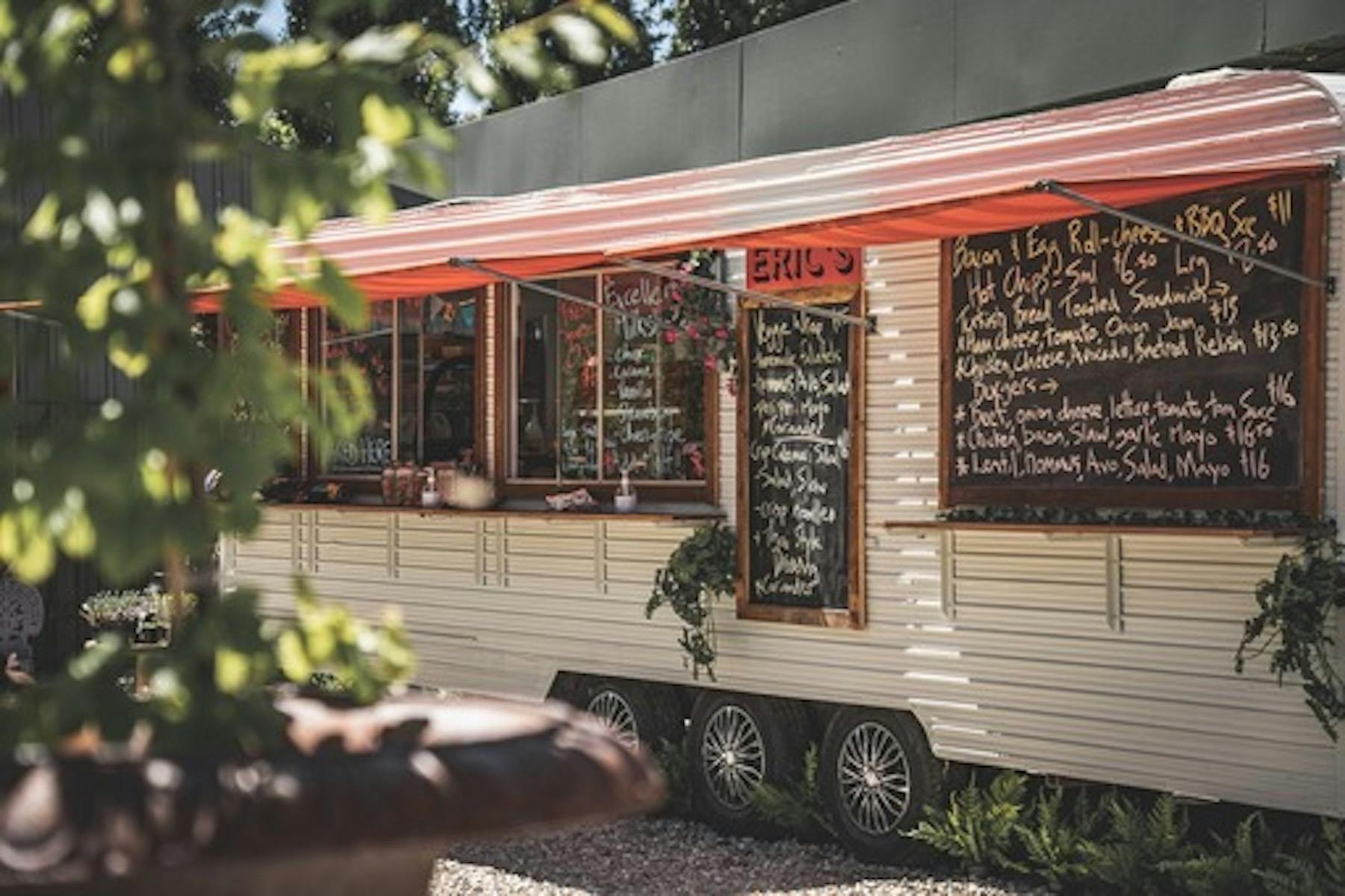 View of the front of Eric's food van with menu on blackboards,  serving window and awnings.
