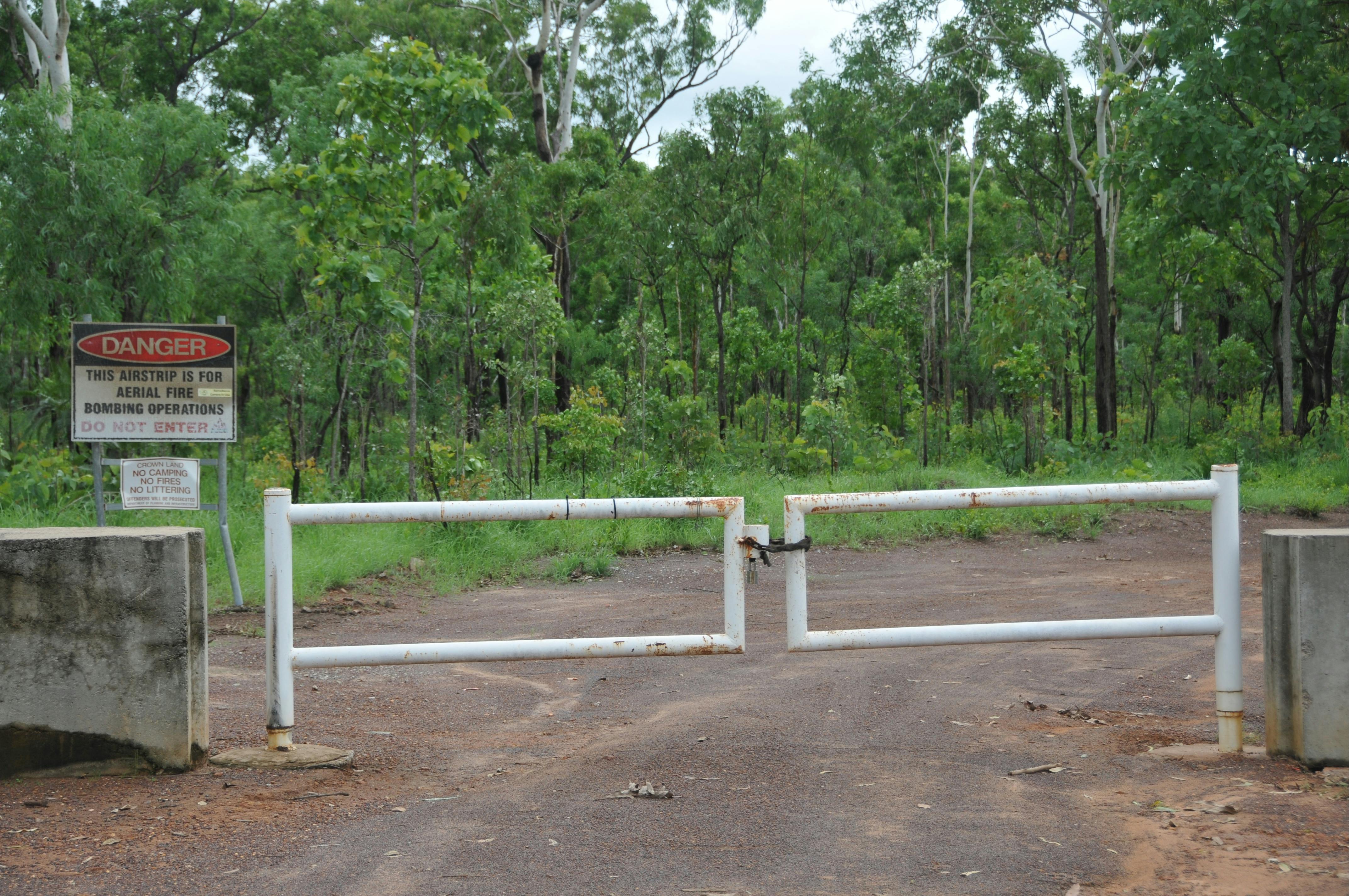 Entrance track leading to the airfield that is closed and signs warn not to enter.