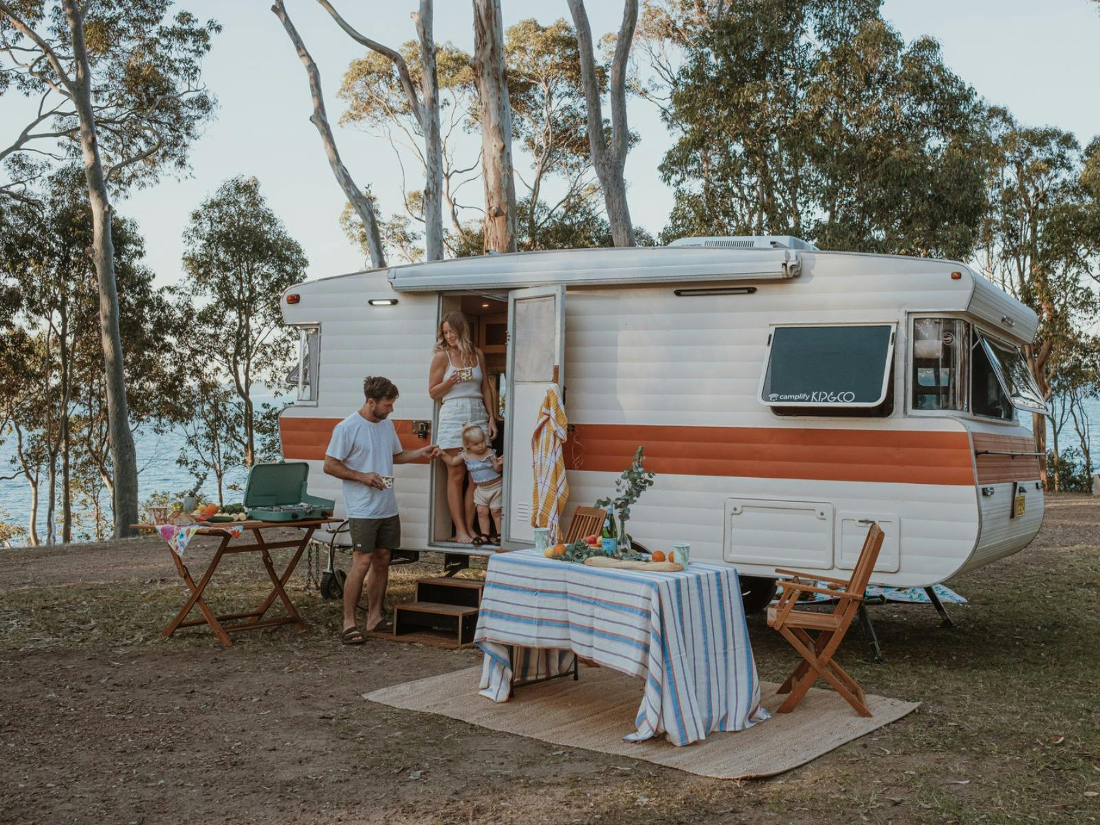 A family stands in the doorway of a vintage caravan
