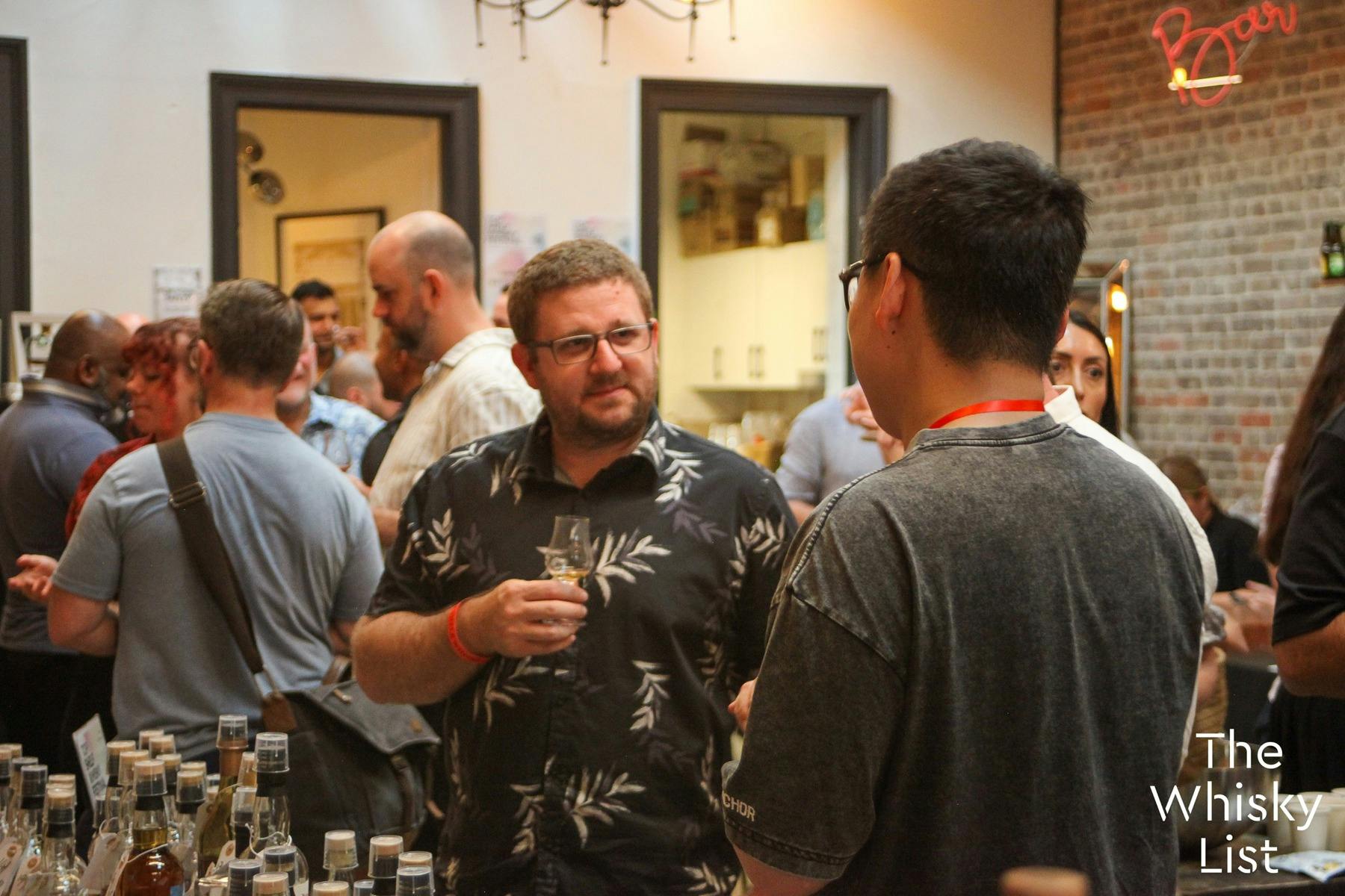 A guest chats with an exhibitor about the products he is tasting.
