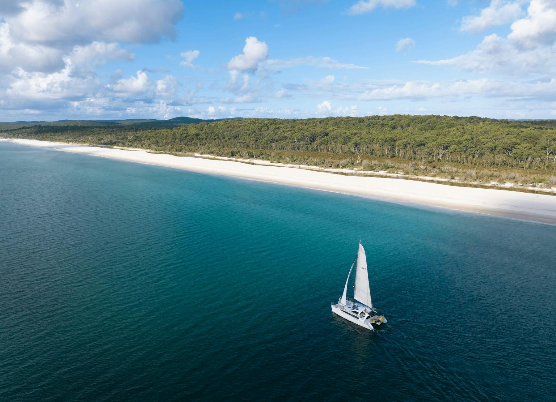 Drone shot of catamaran sailing along the west coast of K'gari - Fraser Island