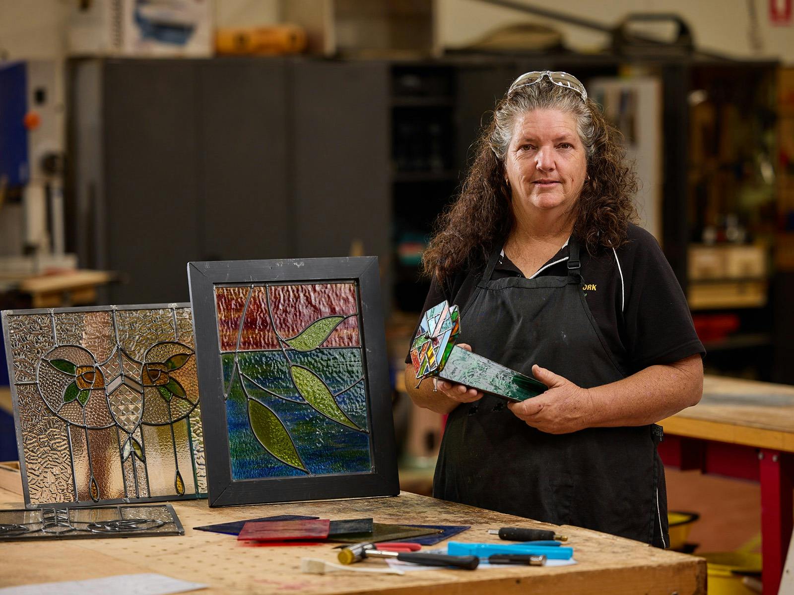 Woman displaying created stained-glass panels. Woman displaying created stained-glass panels.
