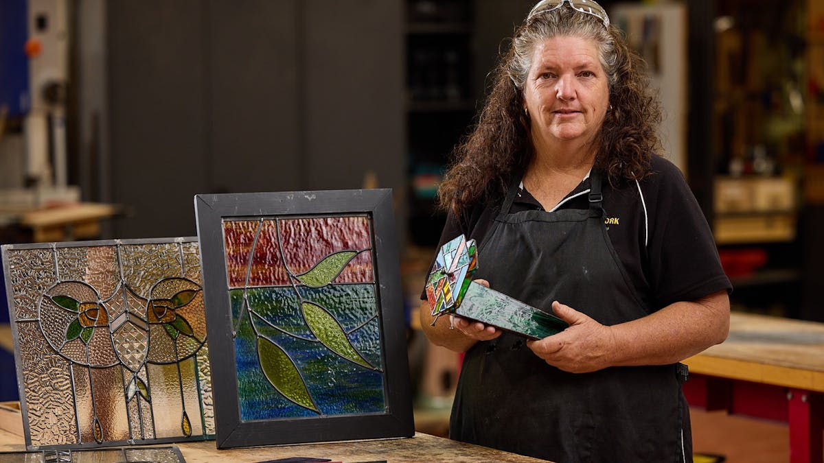 Woman displaying created stained-glass panels.