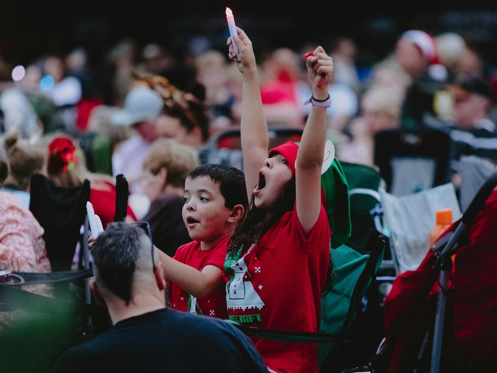 Two children with their hands up in the air  in the crowd.