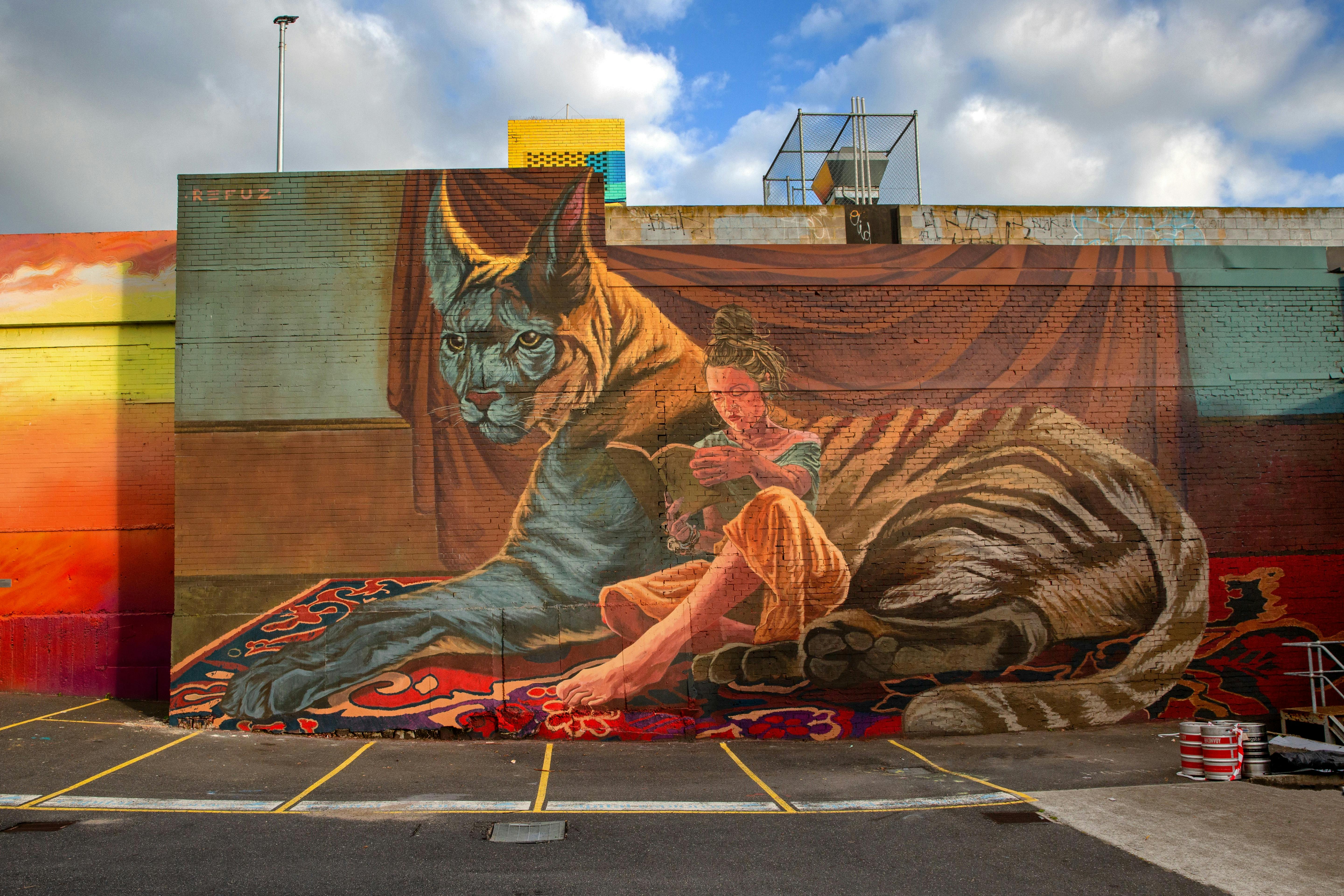 A lady leans against a giant cat, while reading a book. She is not afraid but relaxed.