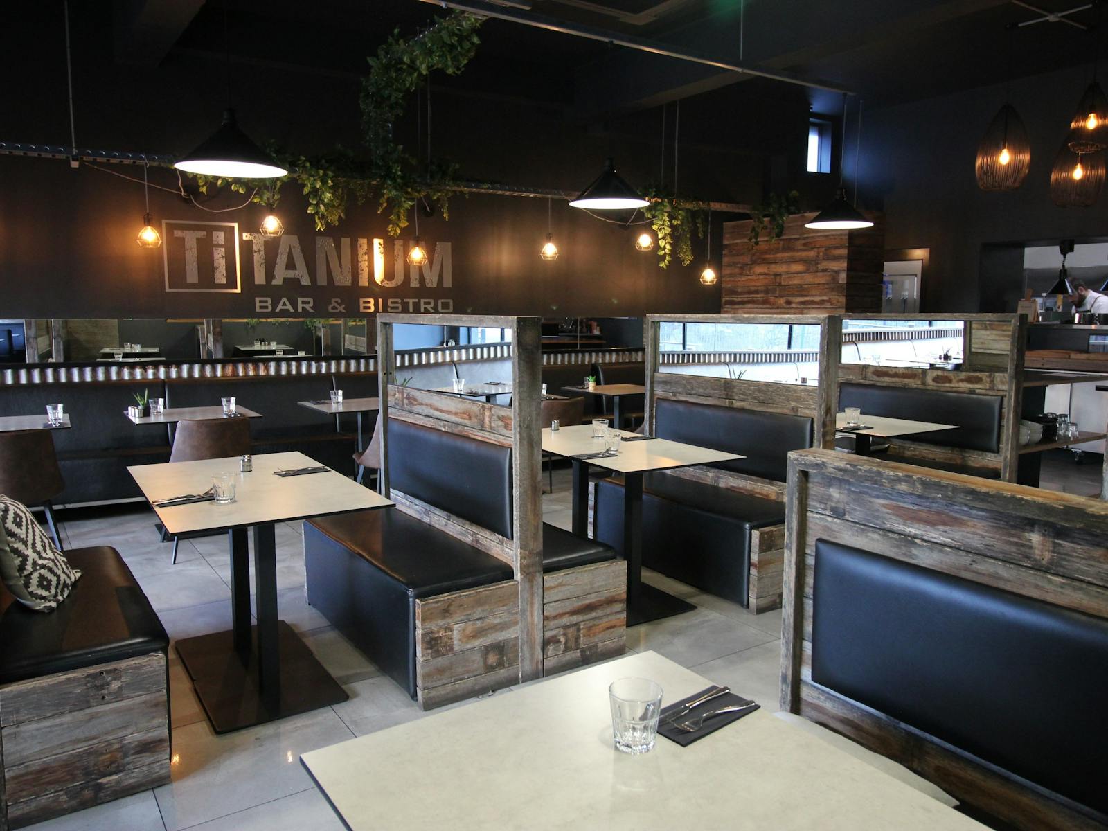 Bistro setting, with two rows of booth tables, wall with small table settings, natural colours.