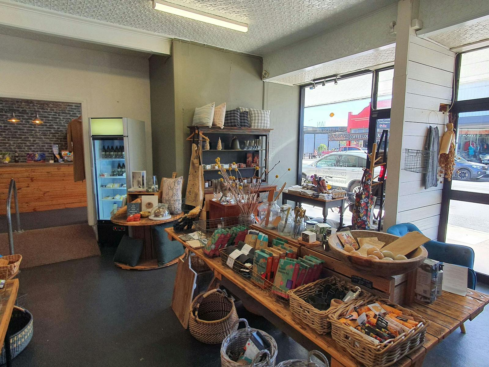 Interior of a shop, with white walls, a wooden table with a colourfil display, and windows