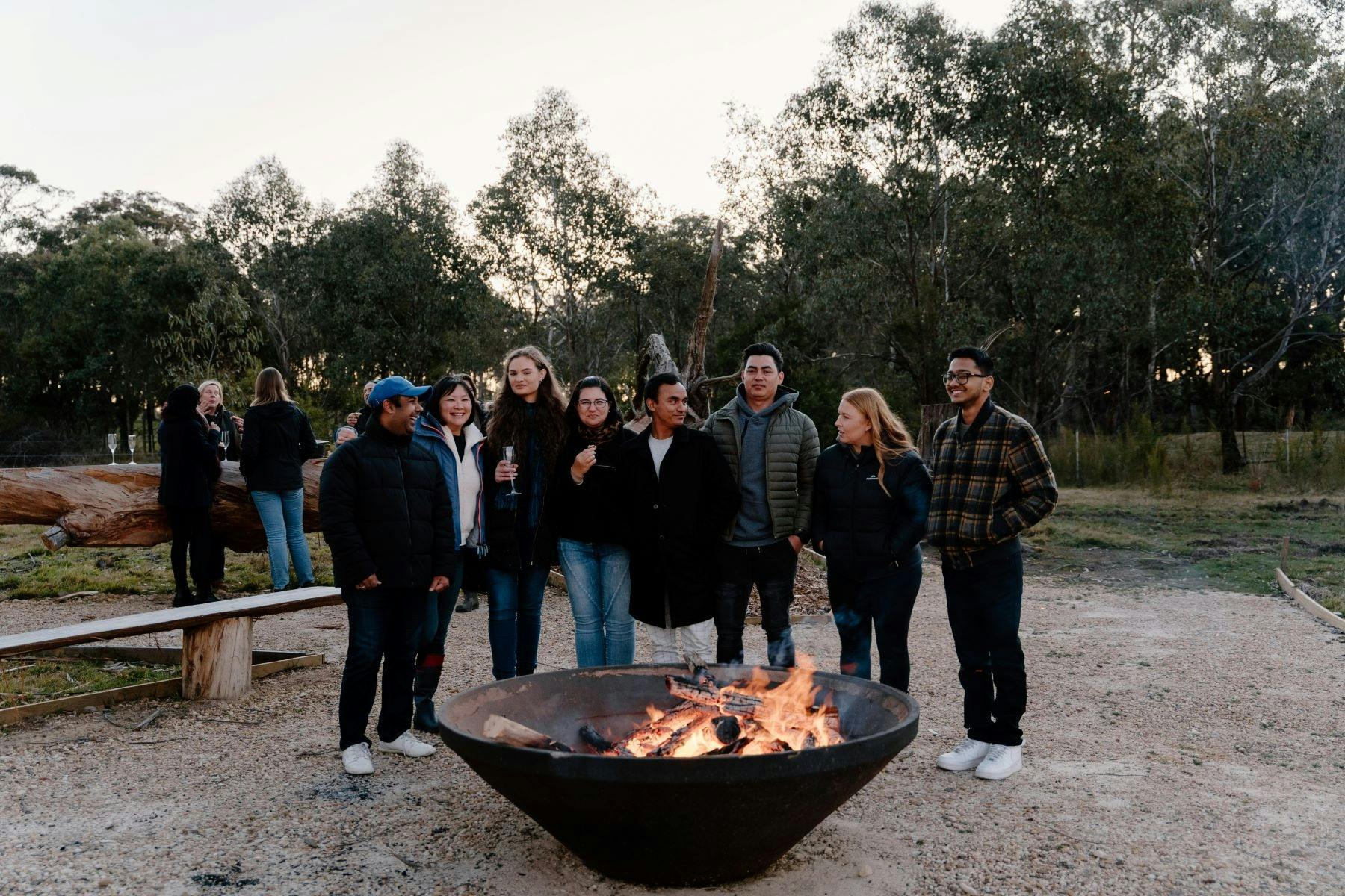 Corporate team gathered around the outdoor firepit in winter