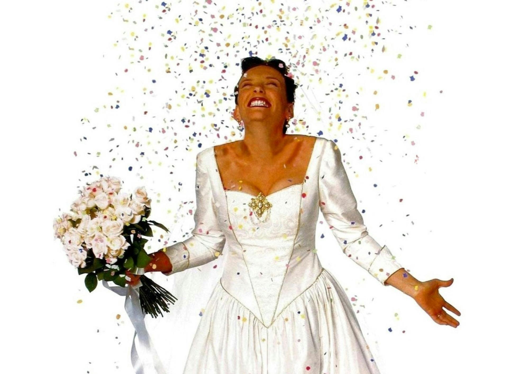 Picture of Muriel from Muriel's Wedding in a white wedding dress holding flowers with confetti above