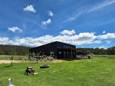 Picture of large grey shed with gardens grass and flowers in front