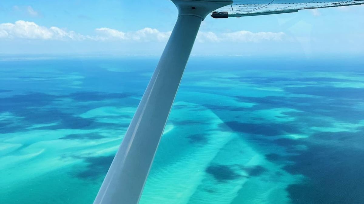 Turquoise blue waters framed by the wing of a plane