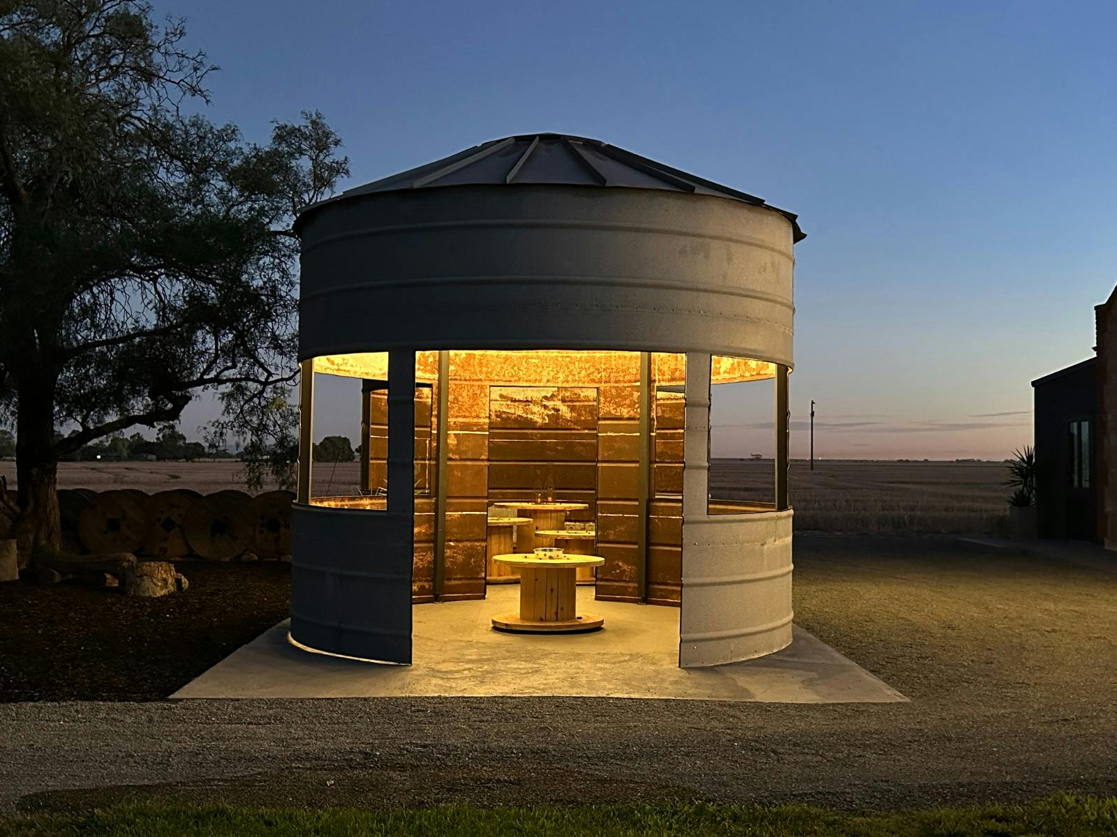 Front view of grain silo gazebos lit at night, glowing warmly with cut-out doors and windows