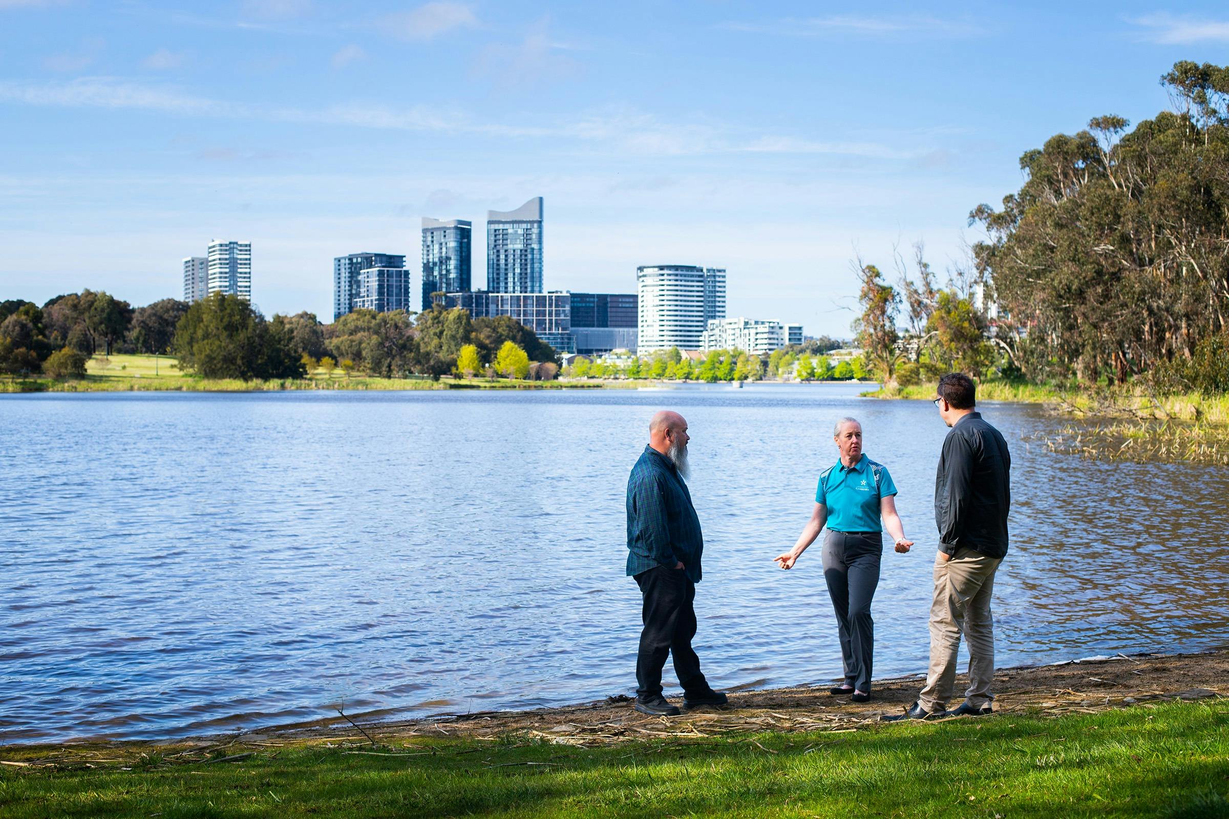 Three researchers talk amongst themselves at the banks of Lake Burley Griffin.