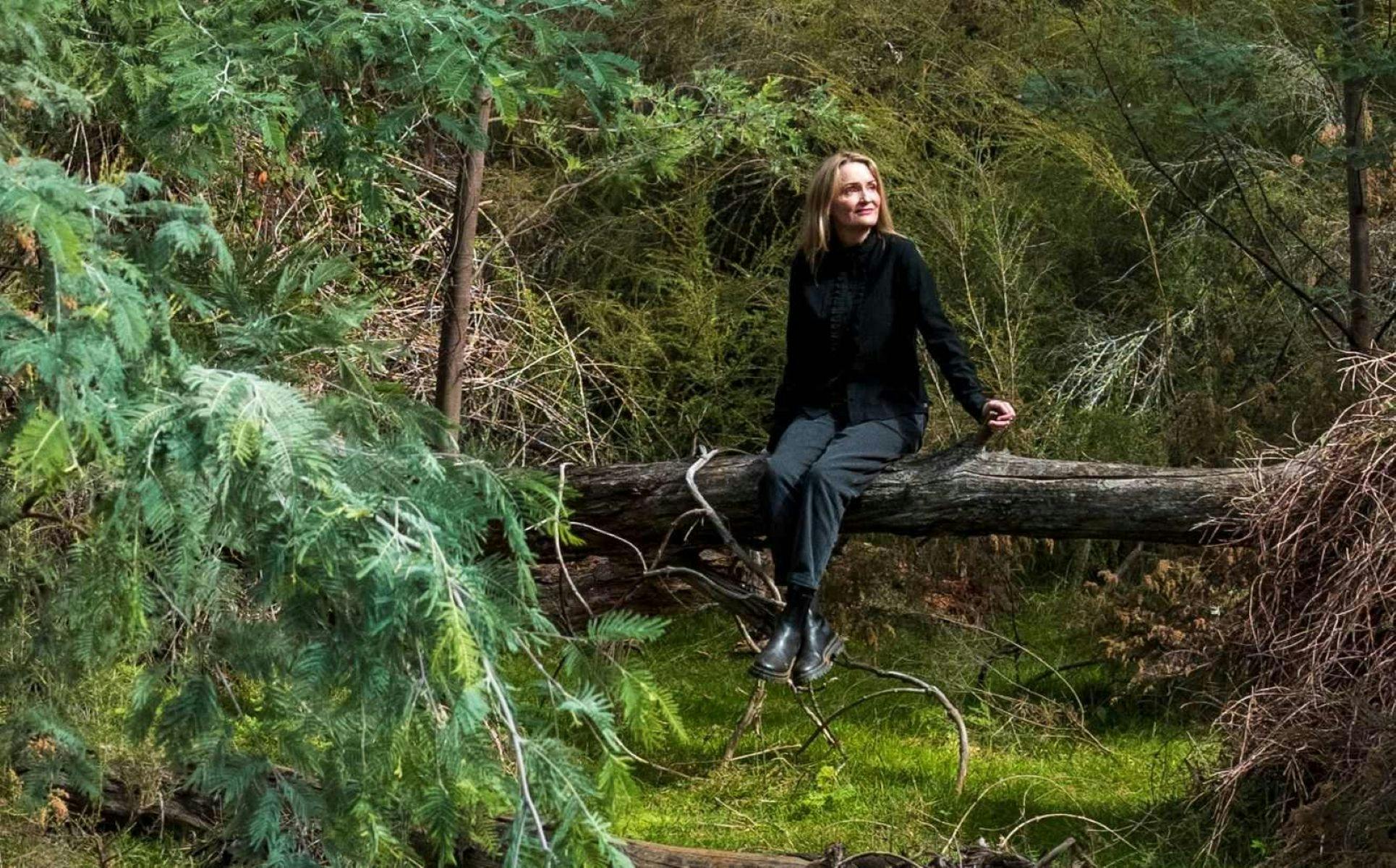 Nicole Welch sitting on an elevated fallen tree, in a forest