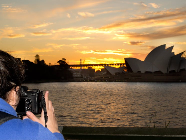 Sunset behind Opera House as photorapher takes photo