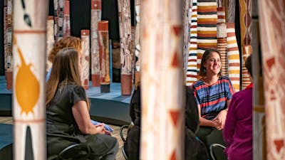 A tour group with an installation of 200 Aboriginal painted logs