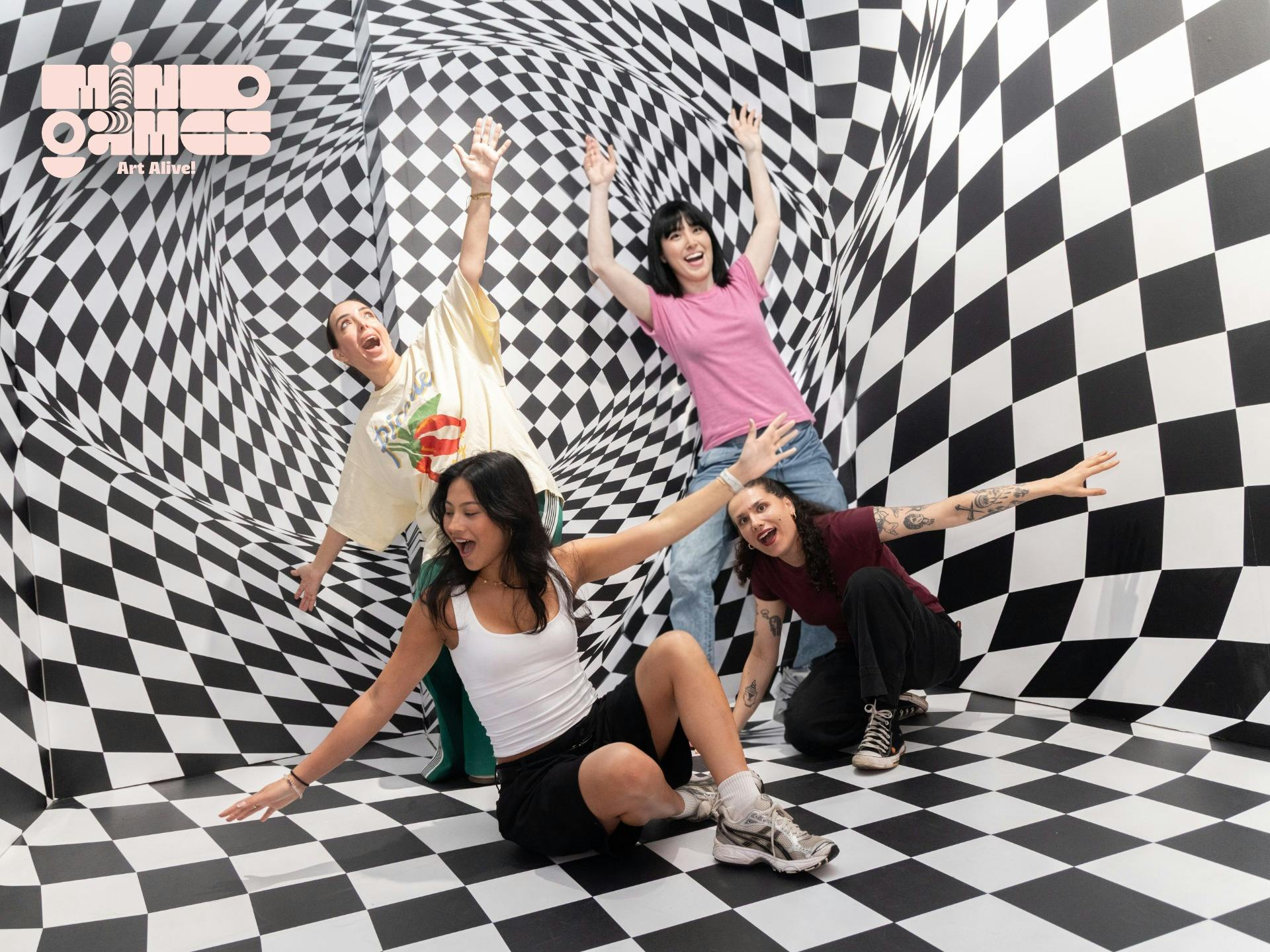 Four visitors interact inside the Wonky Wall exhibit, a black and white geometric illusion room desi
