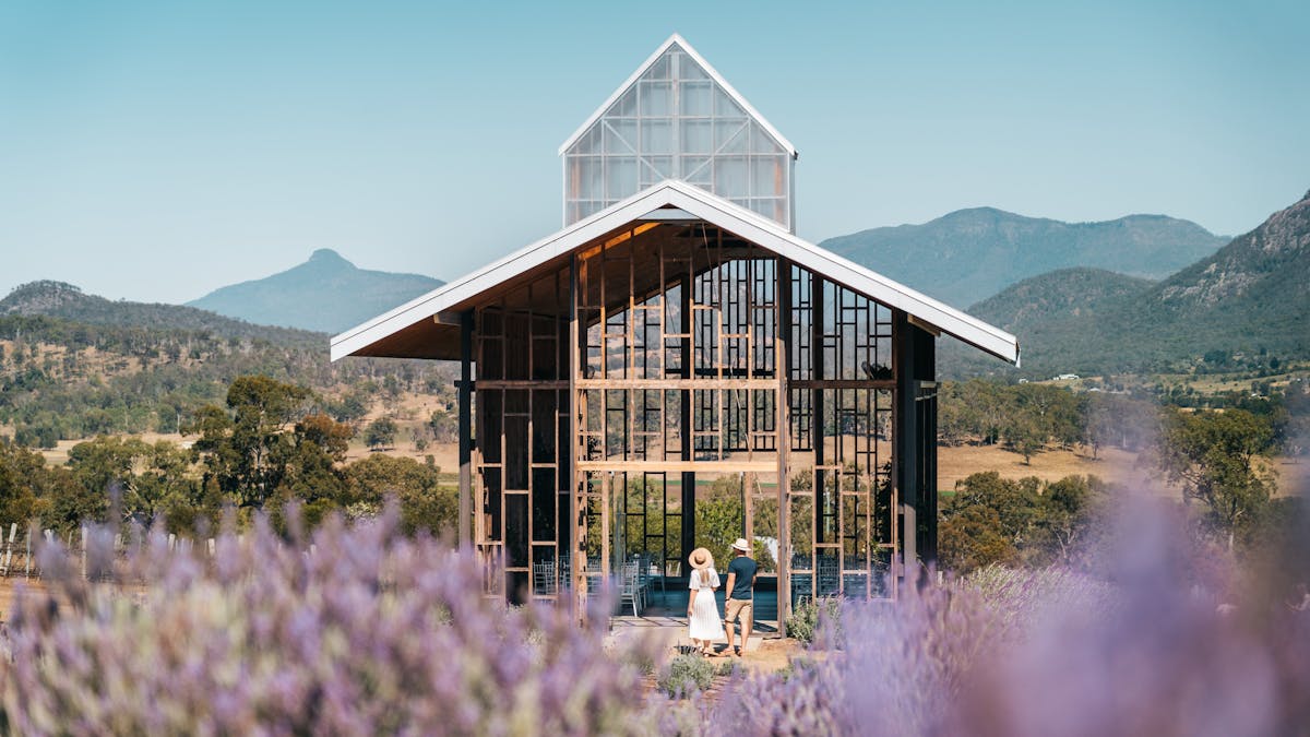 A couple stand before an outdoor chapel situated in a field of lavender at Kooroomba, Scenic Rim A couple stand before an outdoor chapel situated in a field of lavender at Kooroomba, Scenic Rim