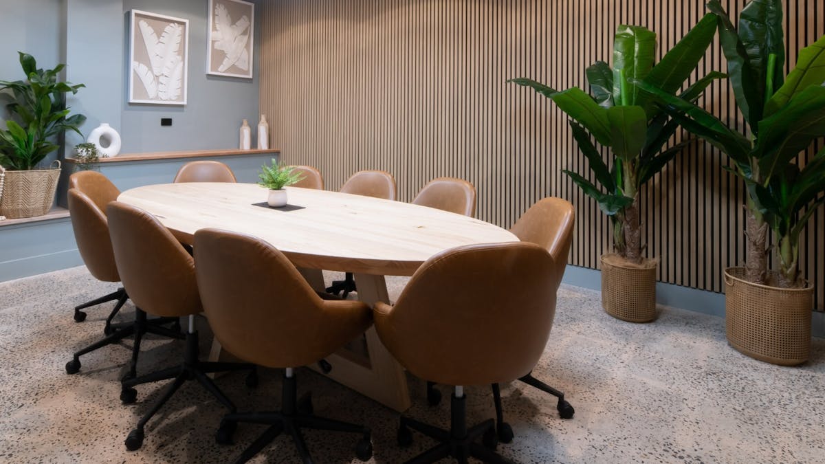 Modern boardroom with large table and screen-sharing technology.