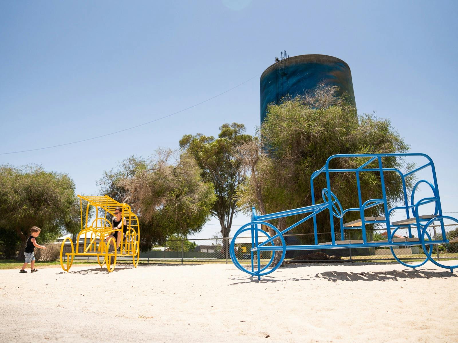 Two vintage car inspired play structures sit in a park